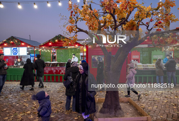 A young Iranian woman speaks with a young boy while standing next to a Yalda decoration during a pomegranate festival on Yalda Night Eve in...