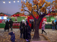 A young Iranian woman speaks with a young boy while standing next to a Yalda decoration during a pomegranate festival on Yalda Night Eve in...