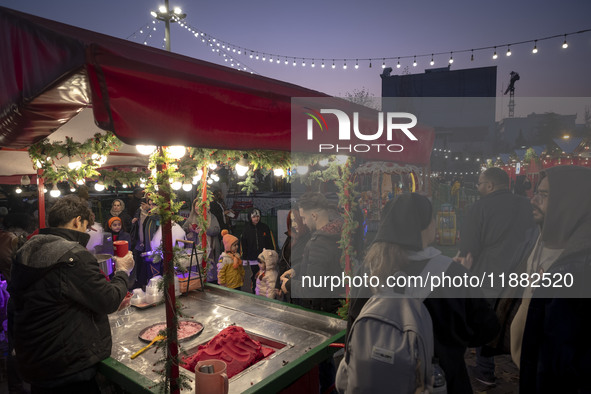 Young Iranian people wait to receive pomegranate ice cream while visiting a pomegranate festival on Yalda Night Eve in the Abasabad tourism...