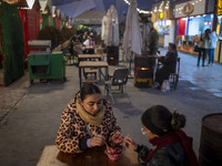 Two young women eat Iranian traditional pomegranate dessert while visiting a pomegranate festival on Yalda Night Eve in the Abasabad tourism...