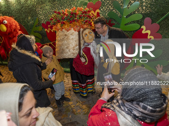 An Iranian man poses for a photograph with a life-size old woman-shaped doll in front of Yalda decorations during a pomegranate festival on...