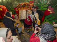 An Iranian man poses for a photograph with a life-size old woman-shaped doll in front of Yalda decorations during a pomegranate festival on...