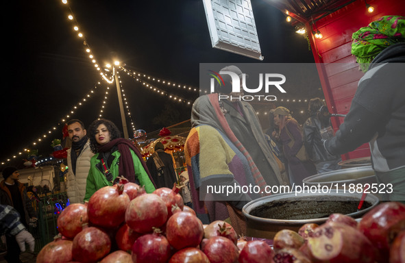 An Iranian elderly couple shops for pomegranate molasses from a saleswoman while visiting a pomegranate festival on Yalda Night Eve in the A...