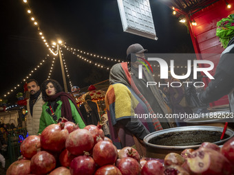 An Iranian elderly couple shops for pomegranate molasses from a saleswoman while visiting a pomegranate festival on Yalda Night Eve in the A...