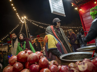 An Iranian elderly couple shops for pomegranate molasses from a saleswoman while visiting a pomegranate festival on Yalda Night Eve in the A...