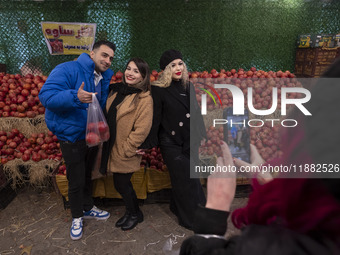 Iranian youths pose for a photograph as one of them carries pomegranates in a plastic bag while shopping for the Yalda Night ceremony during...