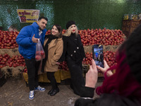 Iranian youths pose for a photograph as one of them carries pomegranates in a plastic bag while shopping for the Yalda Night ceremony during...