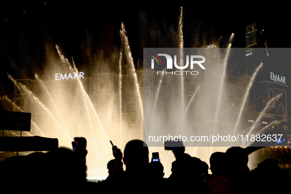 Tourists watch a water show of the Dubai Fountain at Burj Khalifa Lake in Dubai, United Arab Emirates on November 29, 2023.  