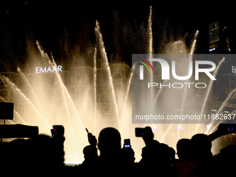 Tourists watch a water show of the Dubai Fountain at Burj Khalifa Lake in Dubai, United Arab Emirates on November 29, 2023.  (