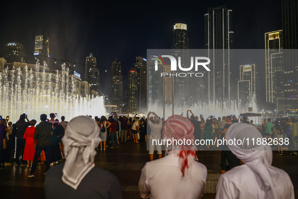 Tourists watch a water show of the Dubai Fountain at Burj Khalifa Lake in Dubai, United Arab Emirates on November 29, 2023.  