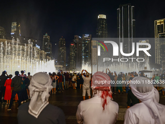 Tourists watch a water show of the Dubai Fountain at Burj Khalifa Lake in Dubai, United Arab Emirates on November 29, 2023.  (