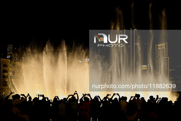 Tourists watch a water show of the Dubai Fountain at Burj Khalifa Lake in Dubai, United Arab Emirates on November 29, 2023.  