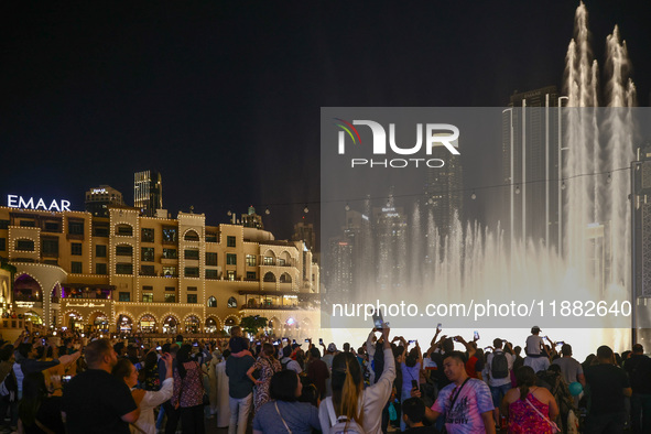 Tourists watch a water show of the Dubai Fountain at Burj Khalifa Lake in Dubai, United Arab Emirates on November 29, 2023.  