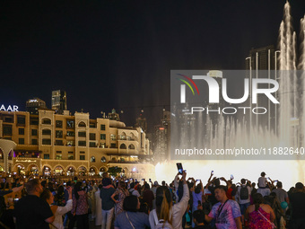 Tourists watch a water show of the Dubai Fountain at Burj Khalifa Lake in Dubai, United Arab Emirates on November 29, 2023.  (