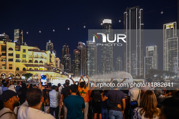 Tourists watch a water show of the Dubai Fountain at Burj Khalifa Lake in Dubai, United Arab Emirates on November 29, 2023.  