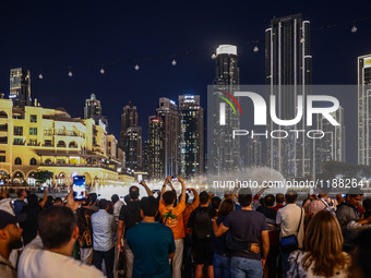 Tourists watch a water show of the Dubai Fountain at Burj Khalifa Lake in Dubai, United Arab Emirates on November 29, 2023.  (