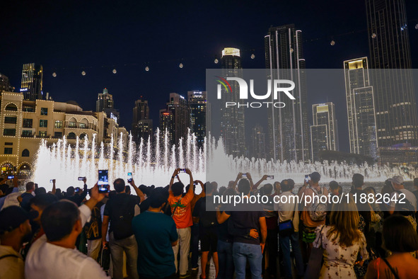 Tourists watch a water show of the Dubai Fountain at Burj Khalifa Lake in Dubai, United Arab Emirates on November 29, 2023.  