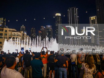 Tourists watch a water show of the Dubai Fountain at Burj Khalifa Lake in Dubai, United Arab Emirates on November 29, 2023.  (