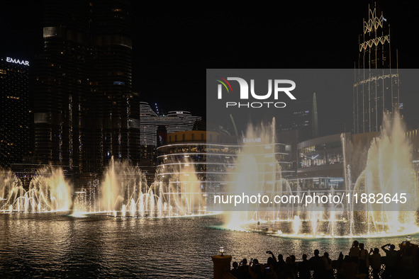 Tourists watch a water show of the Dubai Fountain at Burj Khalifa Lake in Dubai, United Arab Emirates on November 29, 2023.  