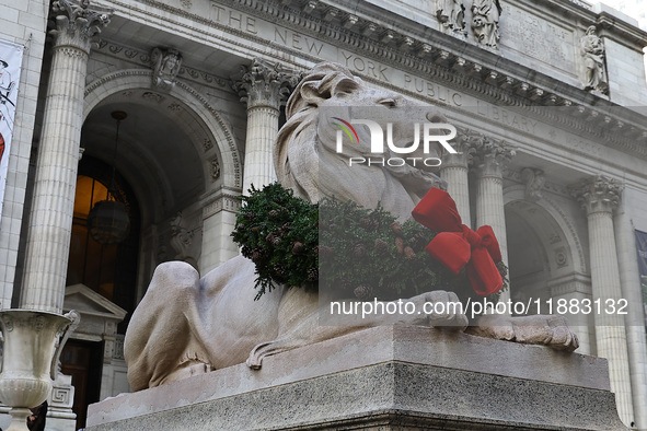 The statue of Patience the lion wears a Christmas wreath around its neck in front of the Beaux-Arts building at Fifth Avenue and 41st Street...