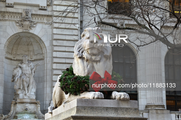 The statue of Fortitude the lion wears a mask and a Christmas wreath around its neck in front of the Beaux-Arts building at Fifth Avenue and...