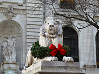 The statue of Fortitude the lion wears a mask and a Christmas wreath around its neck in front of the Beaux-Arts building at Fifth Avenue and...