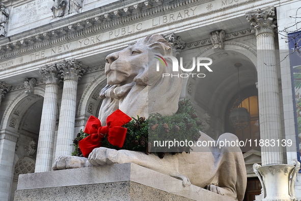 The statue of Fortitude the lion wears a mask and a Christmas wreath around its neck in front of the Beaux-Arts building at Fifth Avenue and...