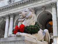 The statue of Fortitude the lion wears a mask and a Christmas wreath around its neck in front of the Beaux-Arts building at Fifth Avenue and...