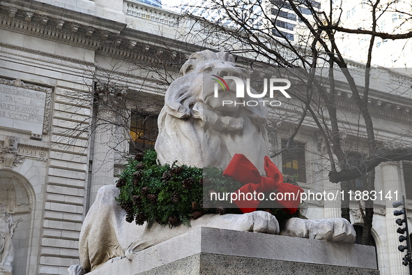 The statue of Fortitude the lion wears a mask and a Christmas wreath around its neck in front of the Beaux-Arts building at Fifth Avenue and...