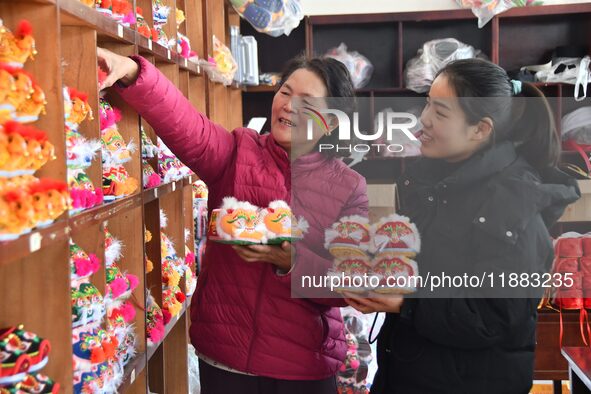 A craftsman selects tigerhead shoes for a customer in Lizhuang village, Zhangxibao town, Yongnian district, Handan, North China's Hebei prov...