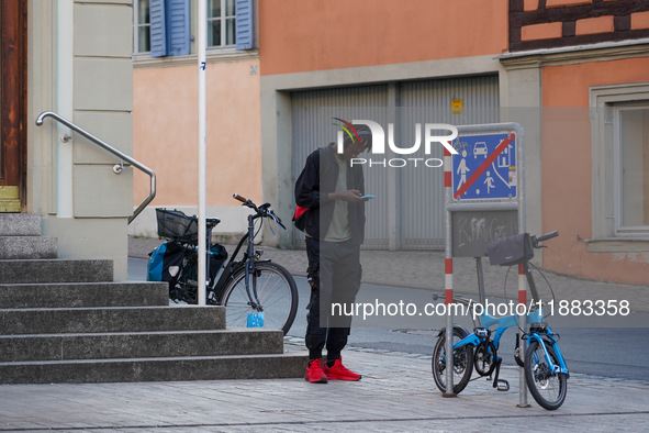 A man stands near parked bicycles while using a smartphone in Bamberg, Bavaria, Germany, on September 9, 2023. 