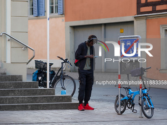 A man stands near parked bicycles while using a smartphone in Bamberg, Bavaria, Germany, on September 9, 2023. (