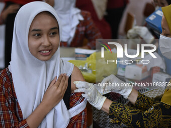 A junior high school student receives an HPV (Human Papillomavirus) vaccine injection from a medical officer in a classroom in Malang, East...