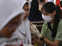 Junior high school students receive the HPV (Human Papillomavirus) vaccine from a medical officer in a classroom in Malang, East Java, Indon...