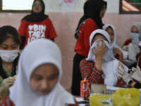 Junior high school students receive the HPV (Human Papillomavirus) vaccine from a medical officer in a classroom in Malang, East Java, Indon...