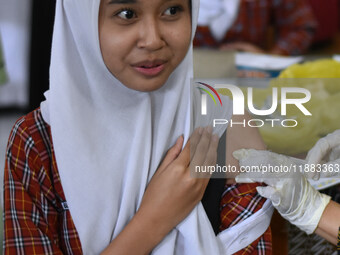 A junior high school student receives an HPV (Human Papillomavirus) vaccine injection from a medical officer in a classroom in Malang, East...