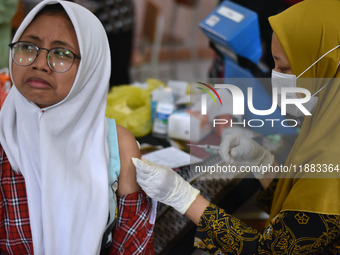 A junior high school student receives an HPV (Human Papillomavirus) vaccine injection from a medical officer in a classroom in Malang, East...