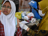 A junior high school student receives an HPV (Human Papillomavirus) vaccine injection from a medical officer in a classroom in Malang, East...