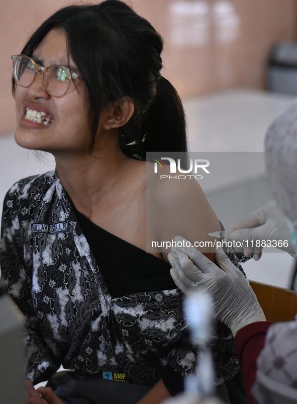 A junior high school student receives an HPV (Human Papillomavirus) vaccine injection from a medical officer in a classroom in Malang, East...