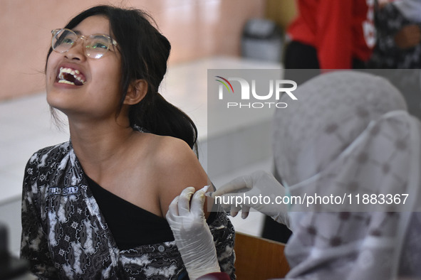 A junior high school student receives an HPV (Human Papillomavirus) vaccine injection from a medical officer in a classroom in Malang, East...