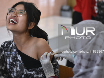 A junior high school student receives an HPV (Human Papillomavirus) vaccine injection from a medical officer in a classroom in Malang, East...