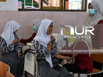 Junior high school students receive the HPV (Human Papillomavirus) vaccine from a medical officer in a classroom in Malang, East Java, Indon...