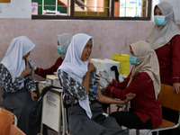 Junior high school students receive the HPV (Human Papillomavirus) vaccine from a medical officer in a classroom in Malang, East Java, Indon...