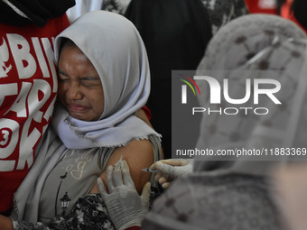 A junior high school student receives an HPV (Human Papillomavirus) vaccine injection from a medical officer in a classroom in Malang, East...