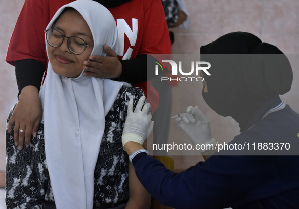 A junior high school student receives an HPV (Human Papillomavirus) vaccine injection from a medical officer in a classroom in Malang, East...