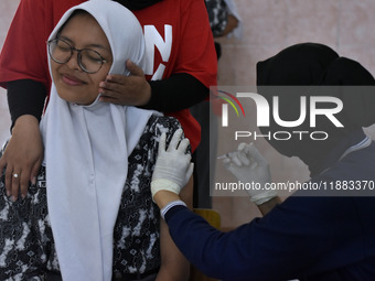 A junior high school student receives an HPV (Human Papillomavirus) vaccine injection from a medical officer in a classroom in Malang, East...