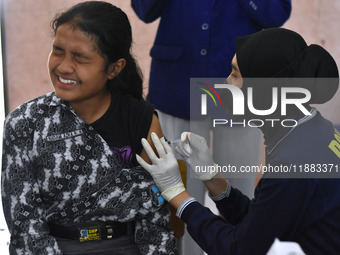 A junior high school student receives an HPV (Human Papillomavirus) vaccine injection from a medical officer in a classroom in Malang, East...