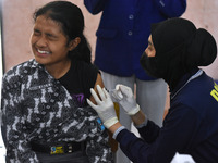 A junior high school student receives an HPV (Human Papillomavirus) vaccine injection from a medical officer in a classroom in Malang, East...