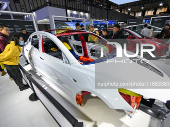 Visitors view a frame-like structure of a Tesla vehicle at the World Intelligent Manufacturing Expo 2024 in Nanjing, China, on December 20,...