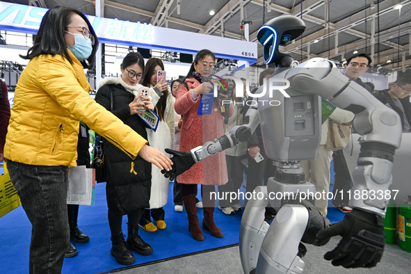 Visitors interact with robots shaking hands at the World Intelligent Manufacturing Expo 2024 in Nanjing, China, on December 20, 2024. 